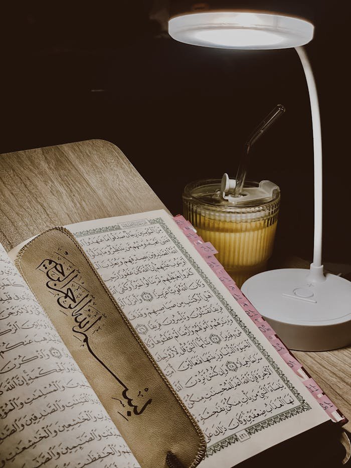 Open Quran with bookmark under a lamp, creating a serene reading ambiance.
