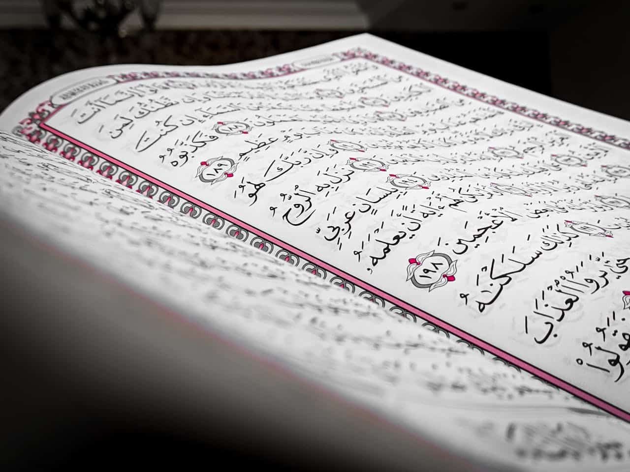 Detailed close-up of an open book showcasing Arabic script, featuring ornamental design and elegant calligraphy.