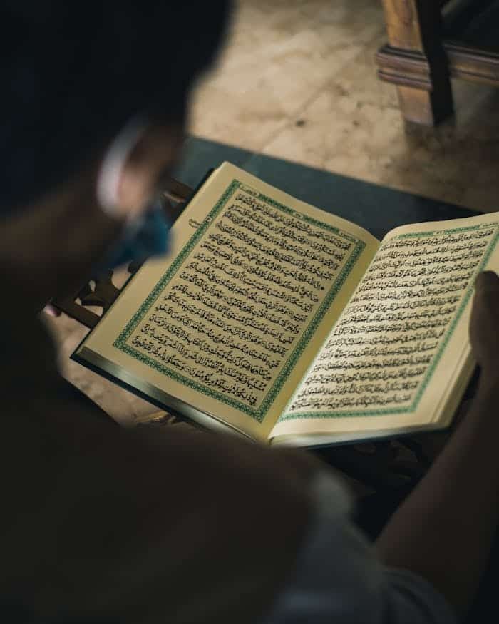 pexels photo 6988372 A thoughtful moment of a Muslim man reading the Quran indoors, capturing faith and spirituality.