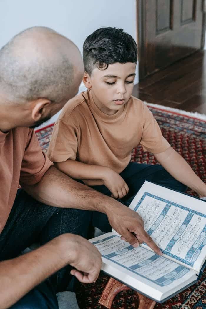 A father teaching his son to read the Koran, signifies Islamic faith and bonding.